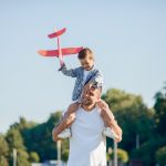 Family in a summer park. Father in a white shirt. Cute little son with an airplane